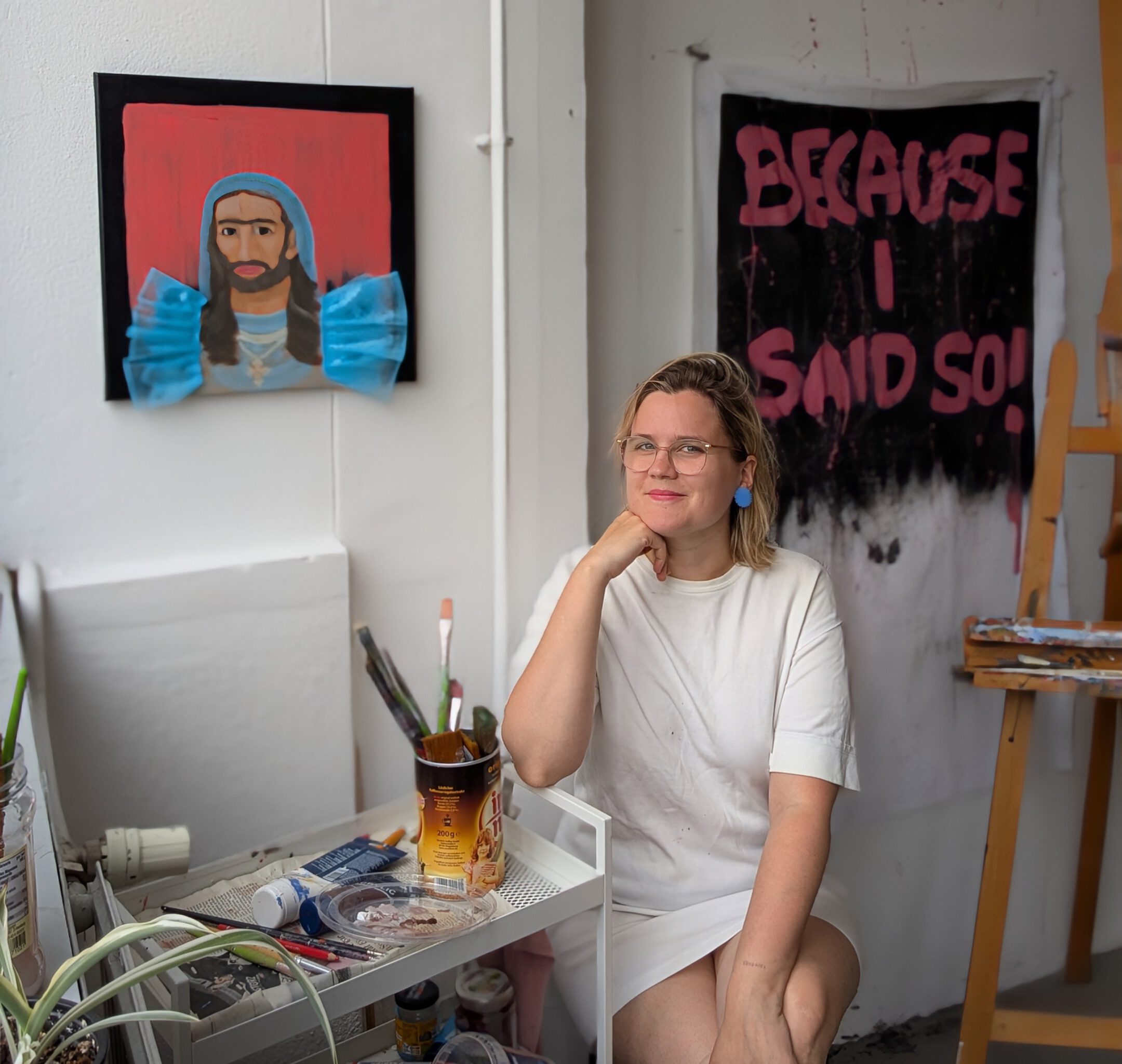 Künstlerinnenporträt_Laura Müller_Studios ID quadrat Laura Müller sitting in front of her paintings in her studio